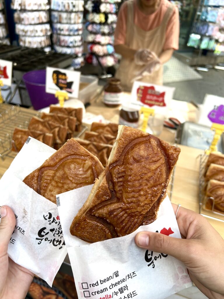 Two hands holding Taiyaki, a japanese snack of pastry shaped like a fish stuffed with custard