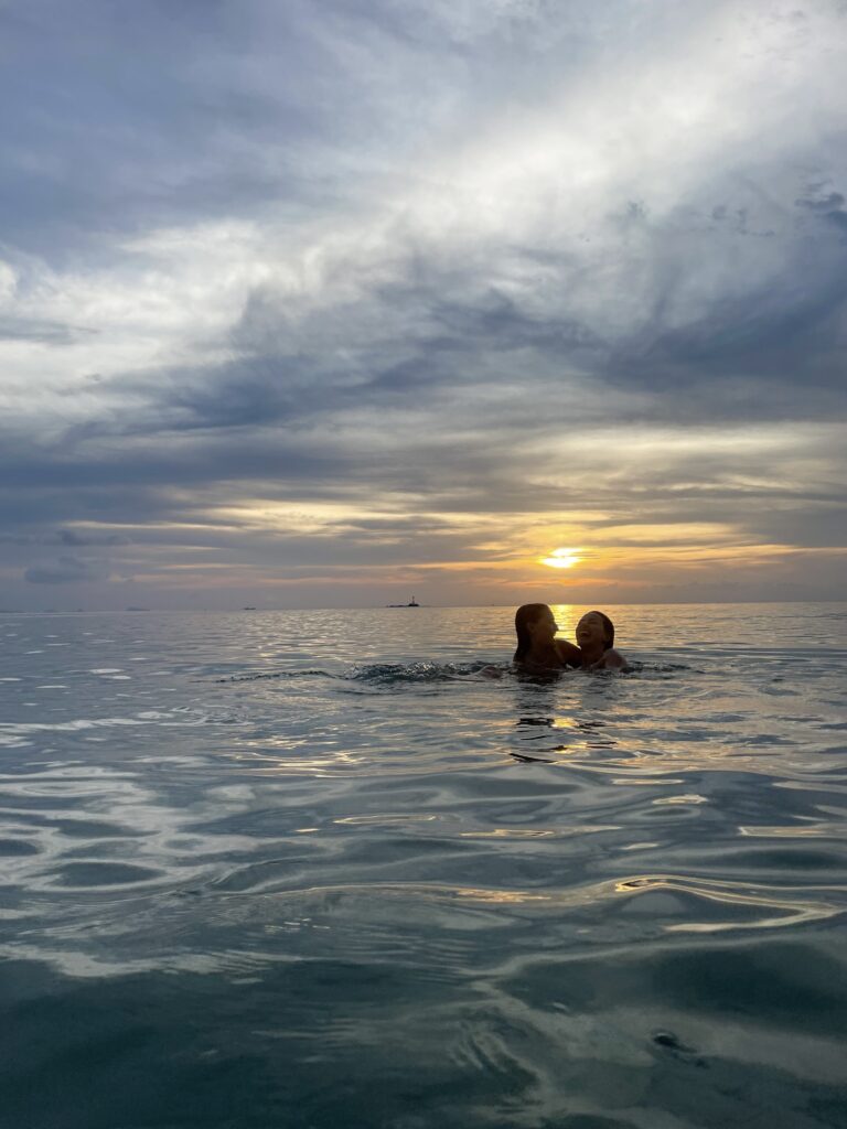 Two girls in the sea at sunset